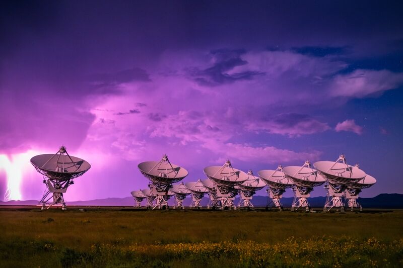 Array of radio telescope dishes under a stormy night sky